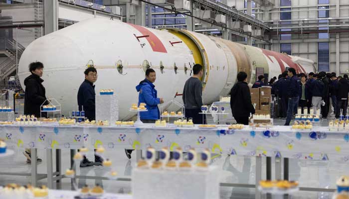 Employees gather during an event next to a test rocket body for the Zhuque-2 program at China’s private rocket company, LandSpaces factory in Huzhou, Zhejiang province, China on December 17, 2025. — Reuters