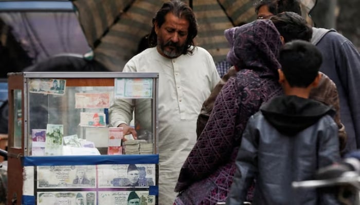 A currency broker stands near his booth, which is decorated with pictures of currency notes, while dealing with customers, along a road in Karachi, Pakistan January 27, 2023. — Reuters