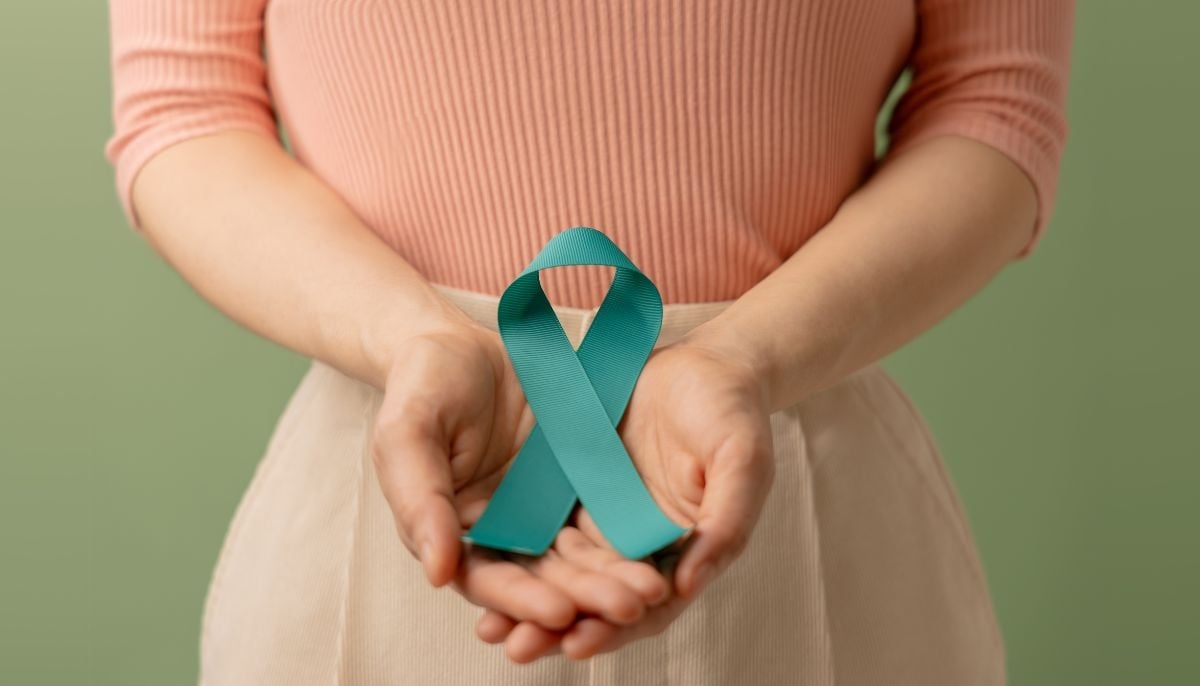 A representational image of a woman holding a teal-coloured ribbon indicating the symbol of cervical cancer awareness. — Canva