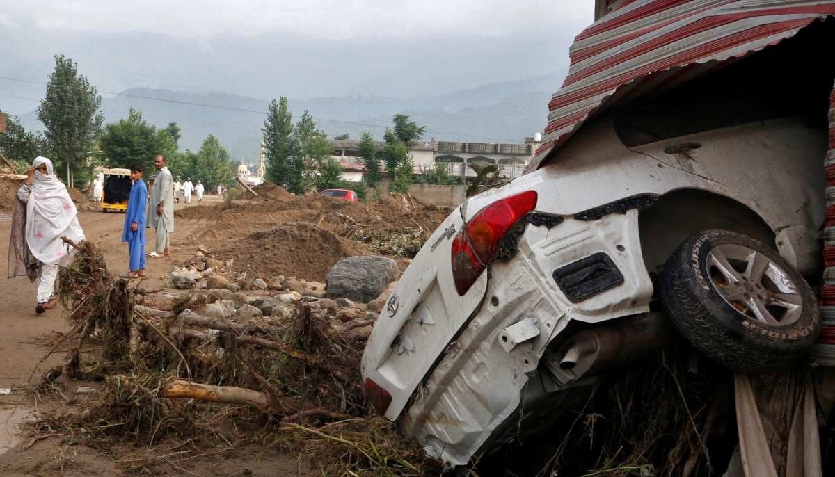 A woman walks past a damaged vehicle following heavy rain and floods in Buner district in Khyber Pakhtunkhwa on August 16, 2025. — Reuters