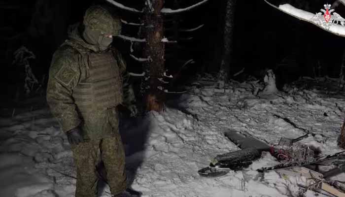 A Russian service member stands next to the remains of a drone, which, according to the Russian Defence Ministry, was downed during the repelling of an alleged Ukrainian attack on the Russian presidential residence in the Novgorod Region, in an unknown location in Russia, in this still image from a video released December 31. — Reuters