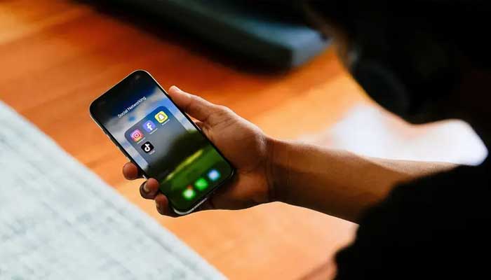 A high school student poses with his mobile phone showing his social media applications. — Reuters/File
