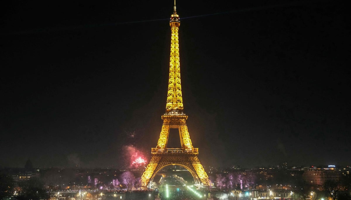 Revellers gather by the Eiffel Tower to welcome in the New Year, in central Paris on December 31, 2025. — AFP