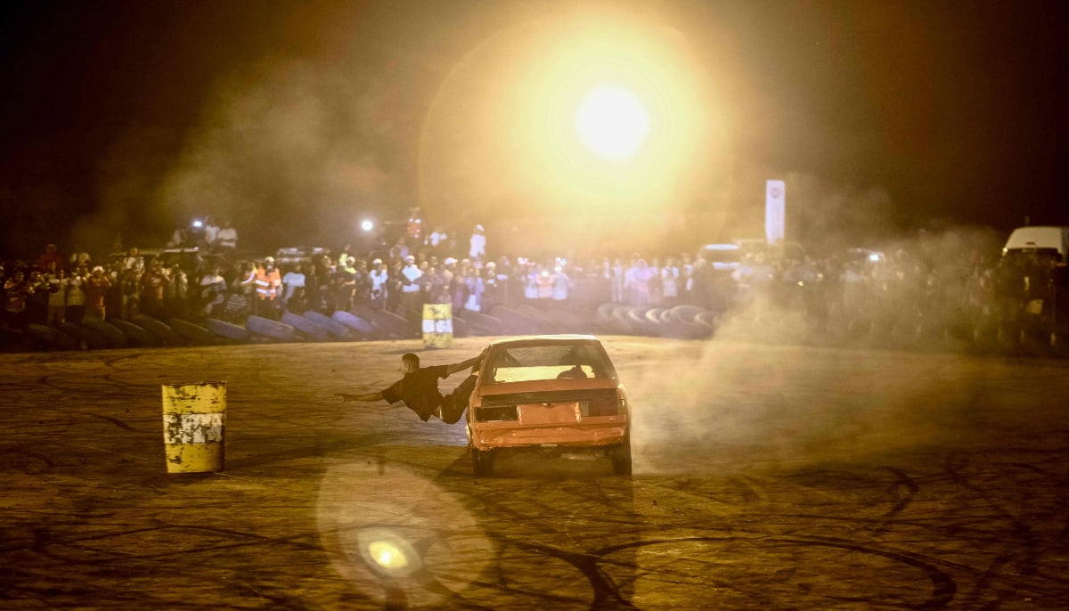 A man gestures as he leans out of a car while spinning during a spinners event at an arena for a crossover gathering on New Year´s Eve in Bulawayo on December 31, 2025. — AFP