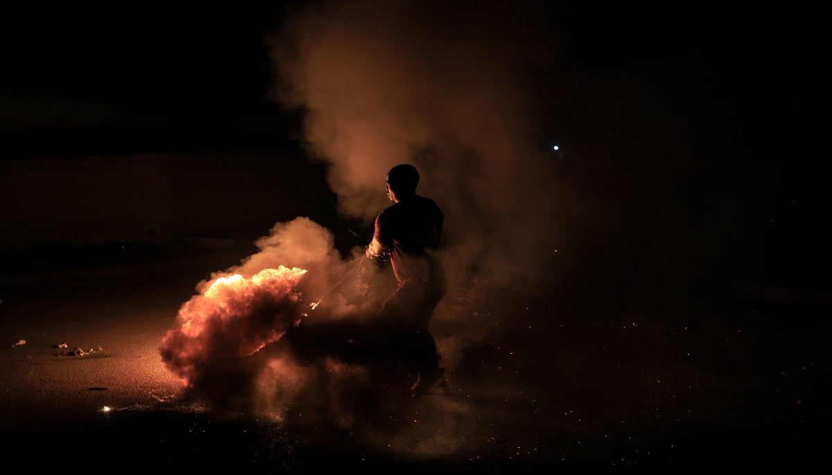 A young man swings a burning tyre in Zone 7 of Sebokeng township, south of Johannesburg, on January 1, 2026. — AFP
