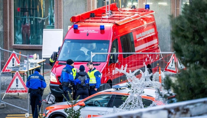 Police officers and rescuers stand next to a firefighters vehicle on the site of an explosion that ripped through the bar Le Constellation in Crans-Montana on January 1, 2026. — AFP