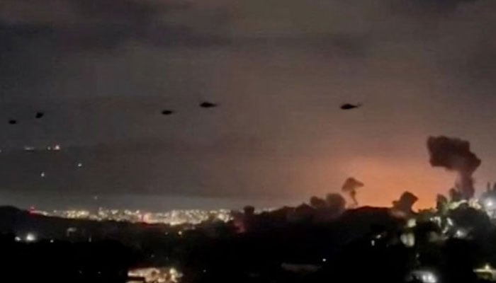 Helicopters fly past plumes of smoke rising from explosions, in Caracas, Venezuela, January 3. — Reuters