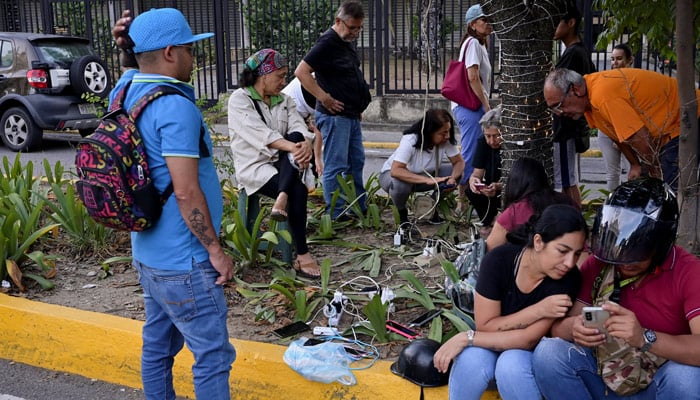 People charge their phones following a blackout in their neighbourhood after the US struck Venezuela and captured its President, Nicolas Maduro, in Caracas, Venezuela, January 3, 2026. — Reuters