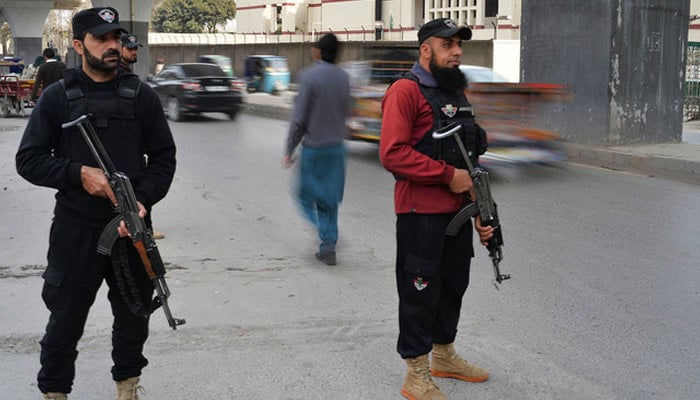 This image shows two police officials standing guard on a road. — AFP/File