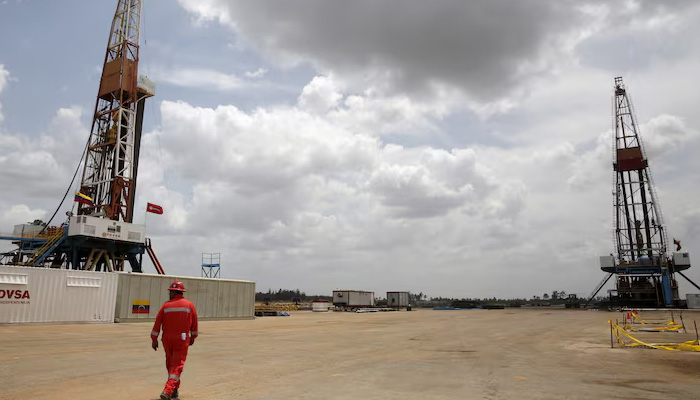 An oilfield worker walks next to drilling rigs at an oil well operated by Venezuelas state oil company PDVSA, in the oil rich Orinoco belt, near Morichal at the state of Monagas. — Reuters/File