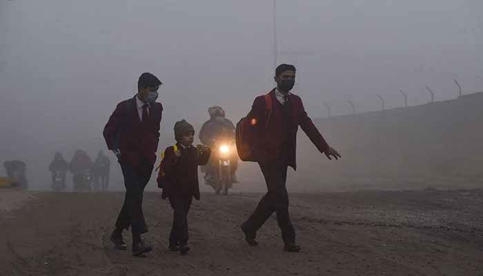 Children walk to their school along a street amid smoggy conditions early in the morning in Lahore. — AFP/File
