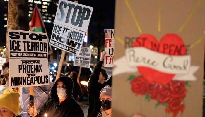 People hold signs and candles during a protest the day after the fatal shooting of Minneapolis resident Renee Nicole Good by an ICE agent, outside the ICE Field Office in Phoenix, Arizona, January 8, 2026.