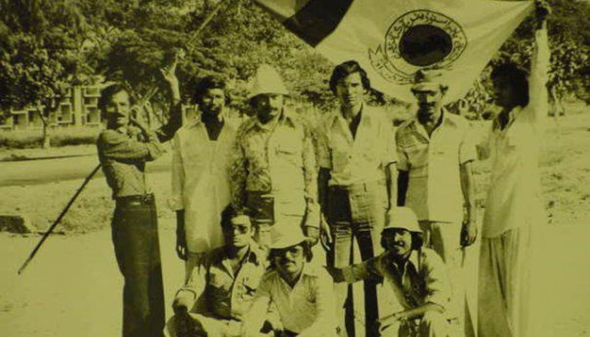 This photograph shows MQM London chief Altaf Hussain in his younger years standing in the centre with the APMSO flag in the backdrop. — X/@AHMERFALASTINI