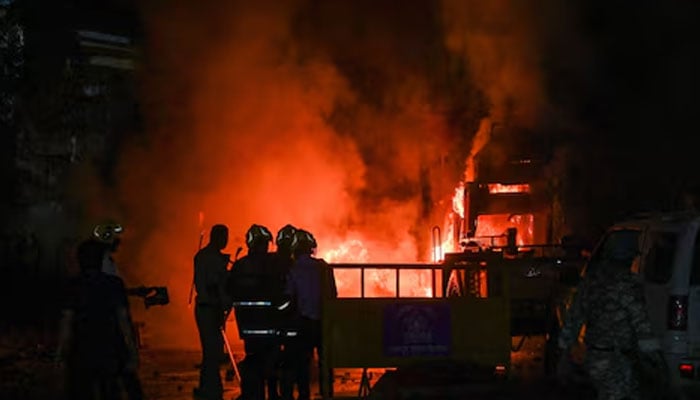 Members of police stand as vehicles burn after clashes erupted due to demands over removal of the tomb of Mughal emperor Aurangzeb, in Nagpur, India, March 17, 2025. — Reuters