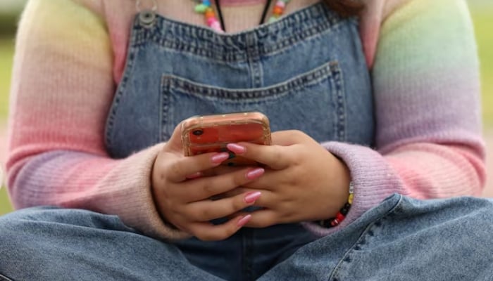 A girl uses her mobile phone in Sydney, Australia, November 22, 2025. — Reuters