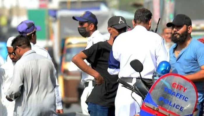 Traffic police officials charge a challan for violating the traffic rules, at Saddar area in Karachi on Tuesday, April 15, 2025. — PPI