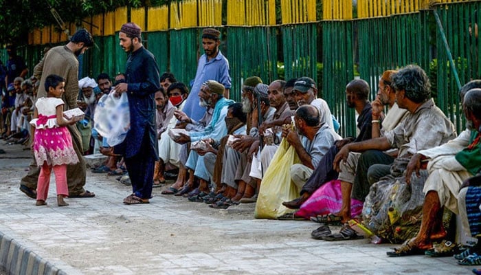 People distribute food to needy people in Karachi. — AFP/File