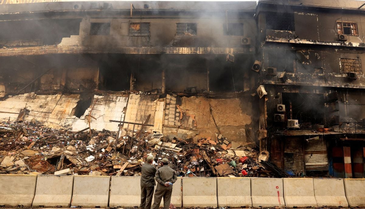 Members from Karachi Municipal Corporation watch as smoke rises from a smouldering building following a massive fire that broke out in the Gul Plaza Shopping Centre in Karachi, January 19, 2026. — Reuter