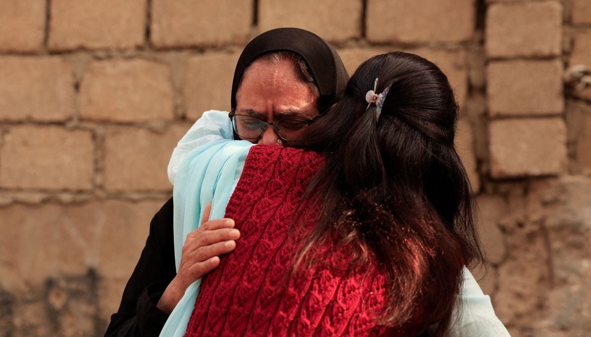 A woman is comforted as she mourns six missing family members who were there shopping for a wedding ceremony, following a massive fire that broke out in the Gul Plaza Shopping Mall in Karachi, January 19, 2026. — Reuters