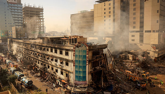 Fire department and municipal workers stand near the site, following a massive fire that broke out in the Gul Plaza Shopping Mall in Karachi on January 20, 2026. — Reuters
