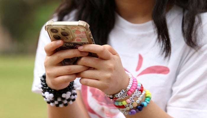 A girl poses holding her phone after an interview discussing Australias social media ban for users under 16, which is scheduled to take effect on December 10, in Sydney, Australia, November 22, 2025. — Reuters