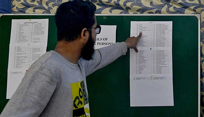 A man checks a list for the name of a missing relative in the aftermath of a massive fire that broke out at a shopping mall in Karachi on January 20, 2026. — AFP