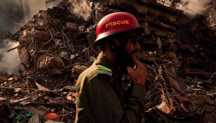 A rescue worker whistles to call his team member (not pictured) as he walks past the collapsed floors, following a massive fire at Gul Plaza Shopping Mall, in Karachi, January 21, 2026. — Reuters