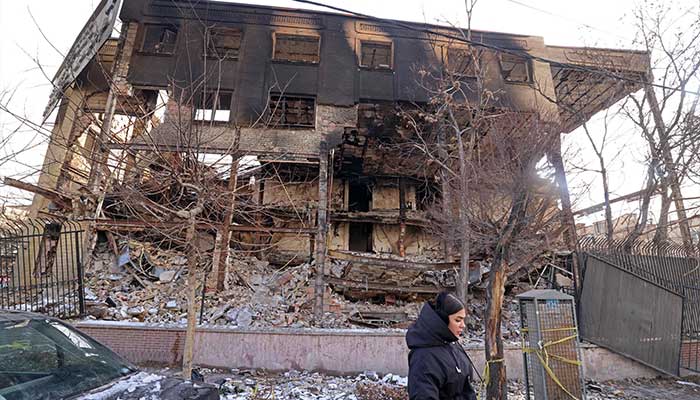 This photograph taken during a tour for foreign media shows a woman walking past a government building that was burnt during recent public protests, in Tehran on January 21, 2026. — AFP