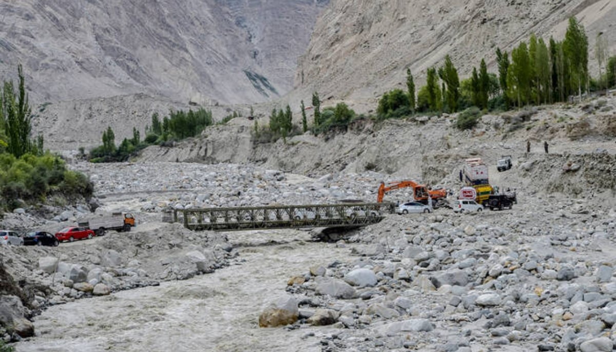 Locals and tourists drive through a temporary bridge after the main bridge was swept away by a lake outburst because of a melting glacier, in Hassanabad village in Gilgit-Baltistan. — AFP/File