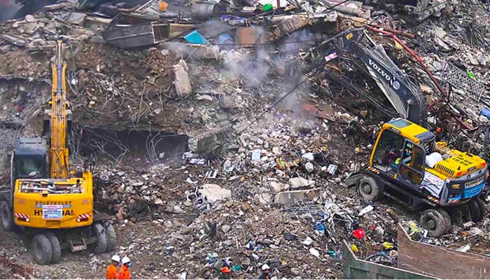 Rescue and emergency team members gather near heavy machinery before starting their search for survivors, following a massive fire that broke out in the Gul Plaza Shopping Mall in Karachi, January 22, 2026. — INP