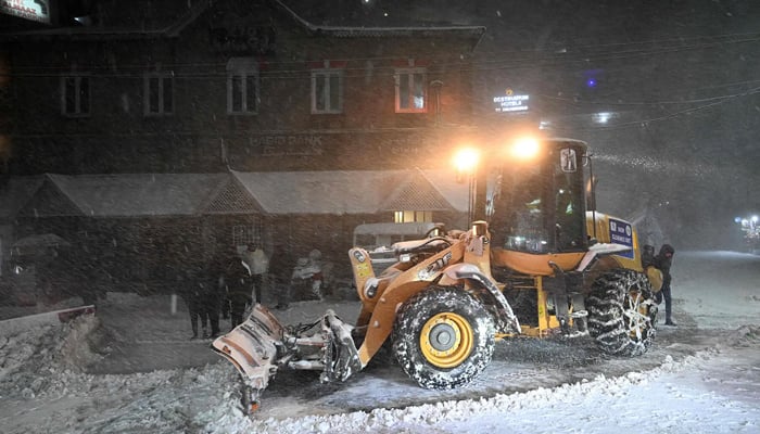 A bulldozer is used to clear heavy snow from a road in Murree on January 23, 2026. — AFP