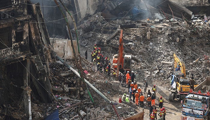 Rescue and emergency team members gather near heavy machinery before starting their search for survivors, following a massive fire that broke out in the Gul Plaza shopping centre in Karachi on January 22, 2026. — Reuters