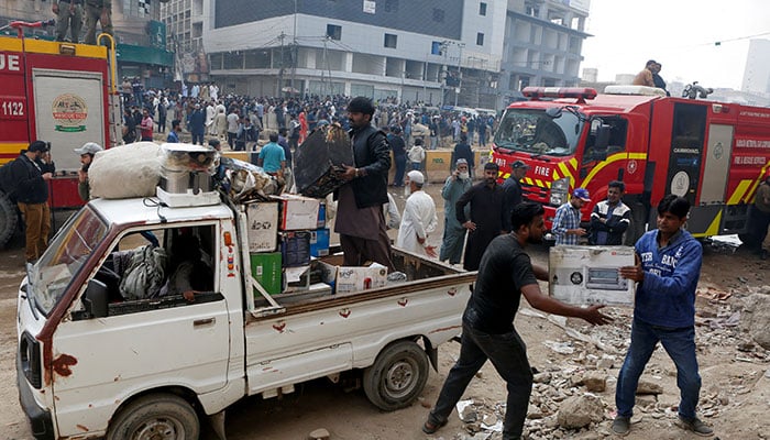 Shopkeepers and workers load a pickup van as they remove their goods from shop after a massive fire broke out in the Gul Plaza shopping centre in Karachi, on January 18, 2026. — Reuters