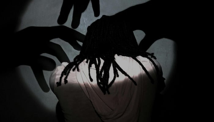 Backview of a person with shadows on the wall representing intrusive thoughts. — Pexels