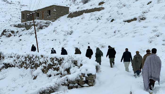 Afghan men walk along a snow-covered path in the Dara district of Panjshir province on January 23, 2026. — AFP