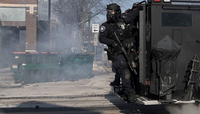 A Minneapolis Police Department officer rides on the back of a vehicle, during clashes with community members at the scene where federal agents fatally shot a man while trying to detain him, in Minneapolis, Minnesota, US, January 24, 2026. — Reuters