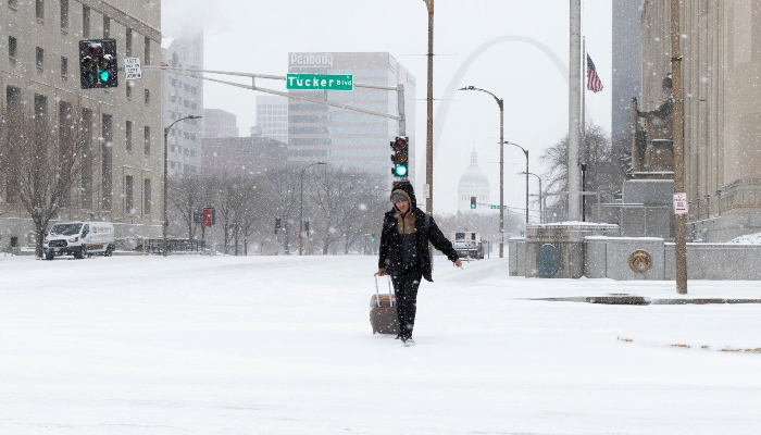 A pedestrian pulls a rolling suitcase through snow‑covered downtown streets as winter weather continues to blanket St. Louis, Missouri, US, January 24, 2026. — Reuters