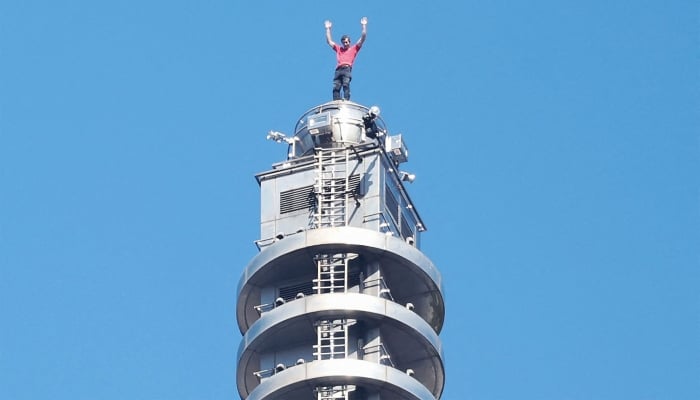 US rock climber Alex Honnold raises his arms from the top of the Taipei 101 building after he successfully free soloed the landmark skyscraper without ropes or safety gear in Taipei on January 25, 2026. — AFP