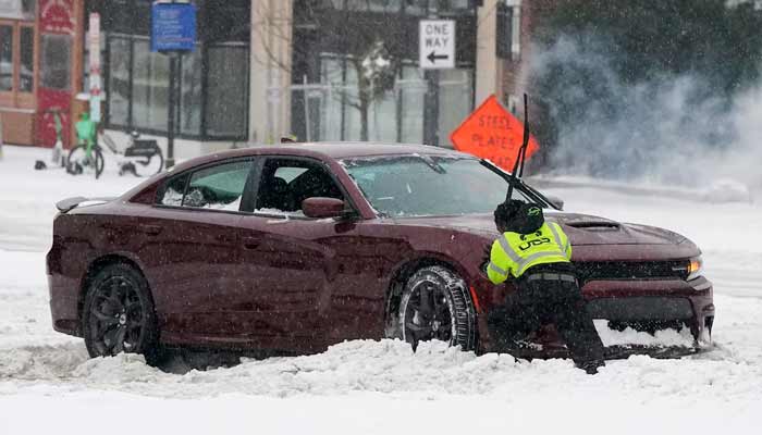 A man helps a stuck driver on Connecticut Ave NW in Washington, DC, US, as a major winter storm spreads across a large swath of the United States, January 25, 2026. — Reuters