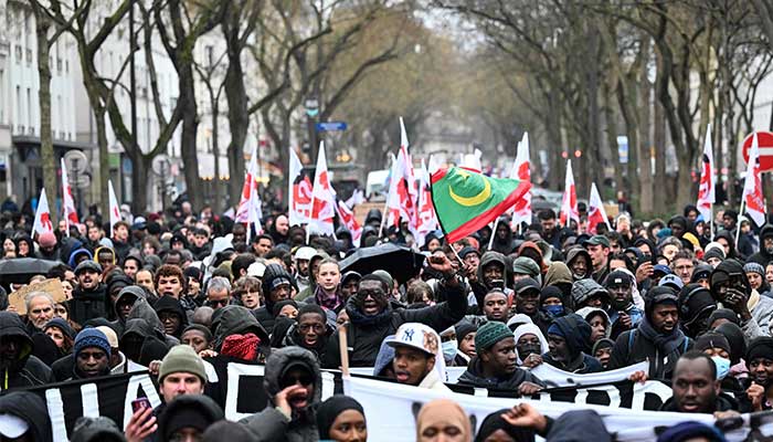 Participants chant slogans, wave flags and show placards and banners as they take part in a march in tribute to 35-year-old El Hacen Diarra, who died in police custody at the police station of Pariss 20th arrondissement, in Paris on January 25, 2026. — AFP