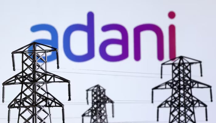 Electric power transmission pylon miniatures and Adani Green Energy logo are seen in this illustration taken on December 9, 2022. — Reuters