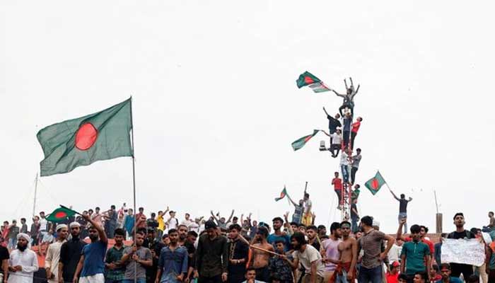 People waves Bangladeshi flags on top the Ganabhaban, the Prime Ministers residence, as they celebrate the resignation of PM Sheikh Hasina in Dhaka, Bangladesh.— Reuters/File