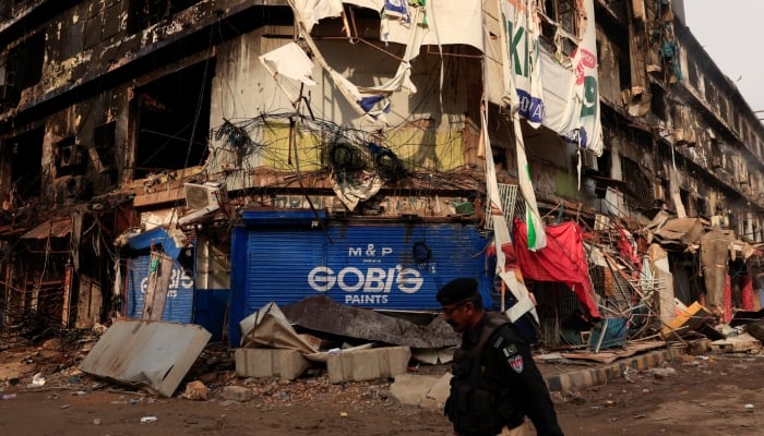 A police officer walks past a damaged building, following a massive fire that broke out in the Gul Plaza Shopping Mall in Karachi, Pakistan, January 22, 2026. — Reuters