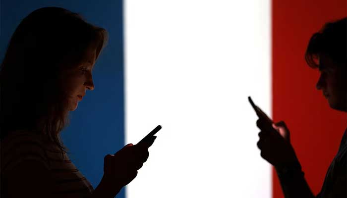 Teenagers pose for a photo while holding smartphones in front of a France flag in this illustration taken September 11, 2025. — Reuters