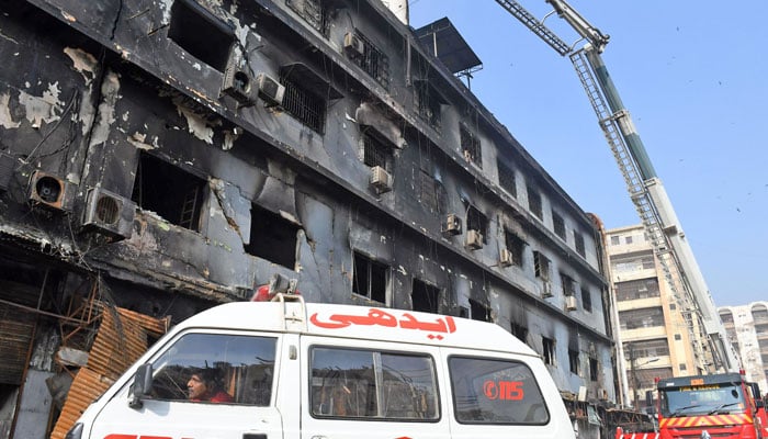 An ambulance is parked in front of Gul Plaza as rescuers take part in search operation after deadly fire in Karachi on January 19, 2026. — Online