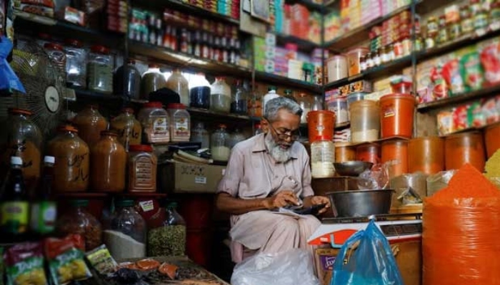 A shopkeeper uses a calculator while selling spices and grocery items at a shop in Karachi. — Reuters/File