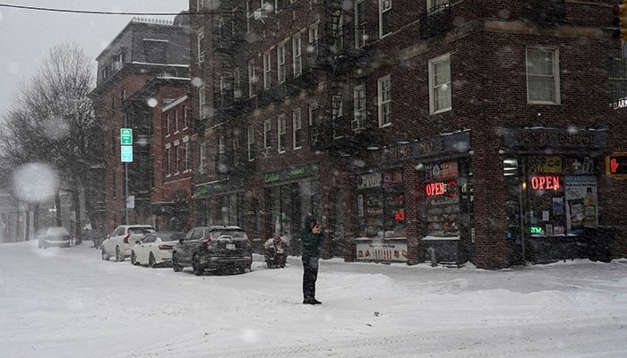 A pedestrian uses his mobile phone to photograph snowfall, as Winter Storm Fern stretches across a large swath of the United States, in Brooklyn, New York City on January 25, 2026. — Reuters