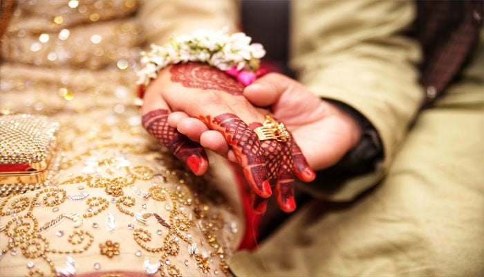A representational image showing a groom holding brides hand. — Unsplash/file