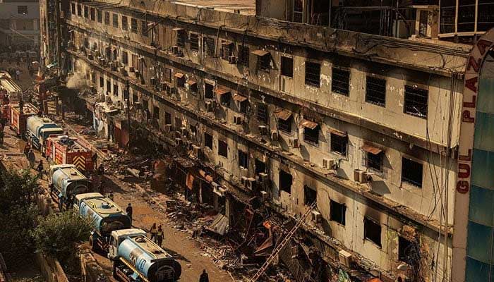 Fire department workers walk past the site, following a massive fire that broke out in the Gul Plaza shopping centre in Karachi on January 20, 2026. — Reuters