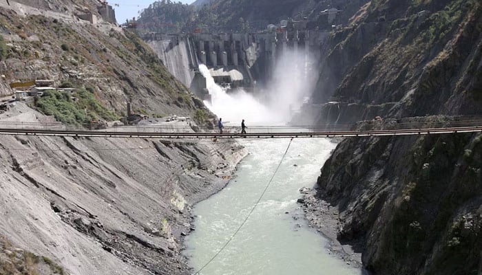 Labourers walk on a bridge near the 450-megawatt hydropower project located at Baglihar Dam on the Chenab River, which flows from India into Pakistan. — Reuters
